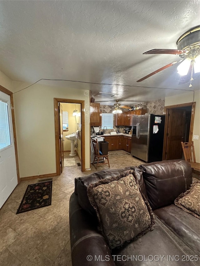 living room with a textured ceiling, ceiling fan, and sink