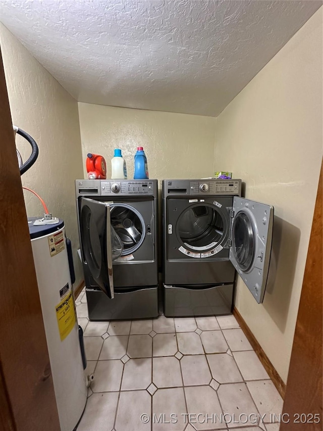 clothes washing area with a textured ceiling, washer and dryer, and electric water heater