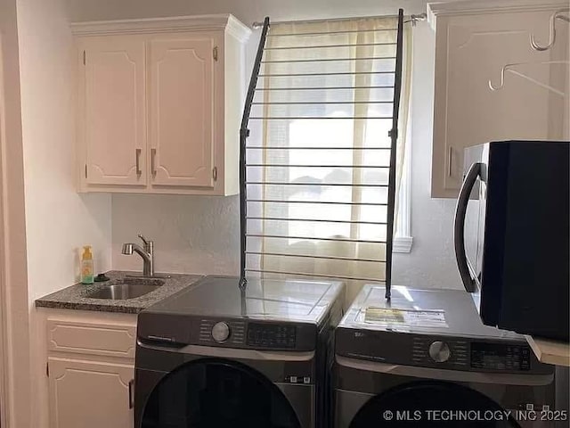 clothes washing area featuring cabinets, sink, and independent washer and dryer