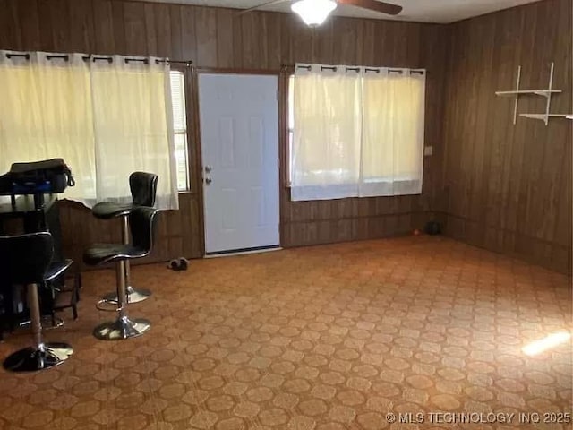 interior space with ceiling fan and wood walls