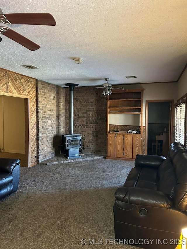 carpeted living room featuring a textured ceiling, ceiling fan, and a wood stove