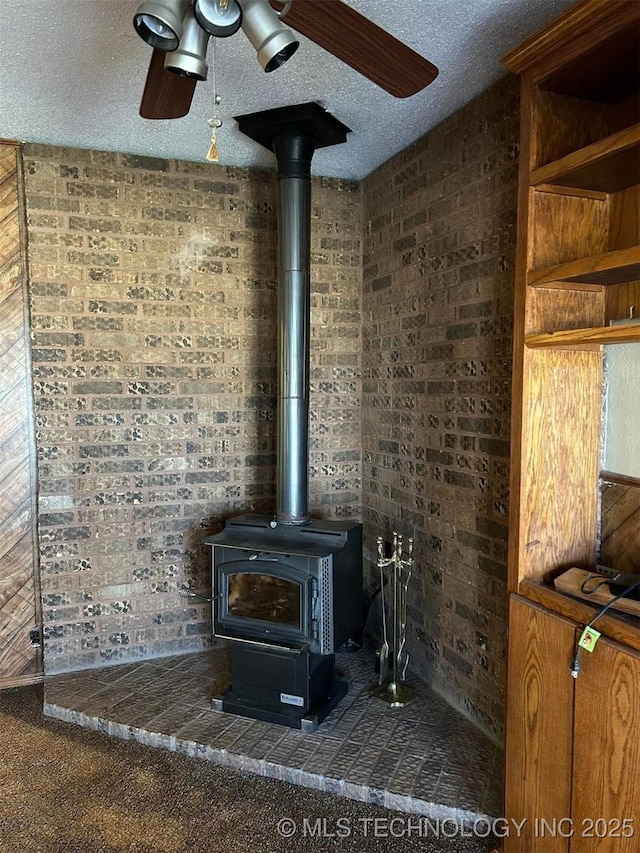 interior details with ceiling fan, a wood stove, a textured ceiling, and carpet floors