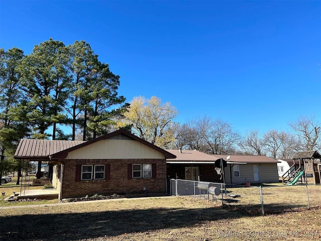 rear view of property featuring a yard and a playground