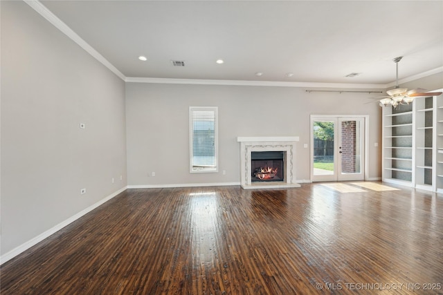 unfurnished living room featuring hardwood / wood-style floors, a high end fireplace, french doors, ceiling fan, and crown molding