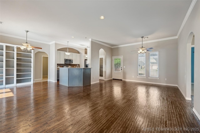 unfurnished living room featuring ceiling fan, dark hardwood / wood-style flooring, and crown molding