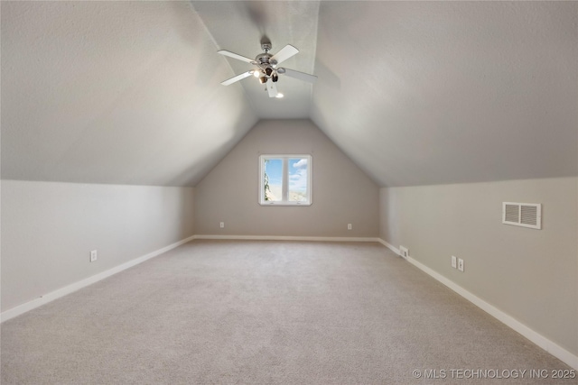 additional living space with light carpet, vaulted ceiling, a textured ceiling, and ceiling fan