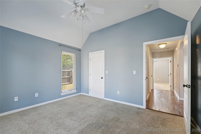 unfurnished bedroom featuring ceiling fan, vaulted ceiling, and carpet flooring