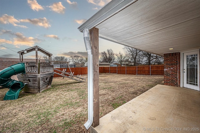 yard at dusk with a patio and a playground