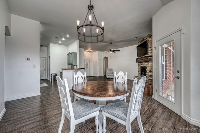 dining room featuring ceiling fan with notable chandelier, dark hardwood / wood-style flooring, and a fireplace