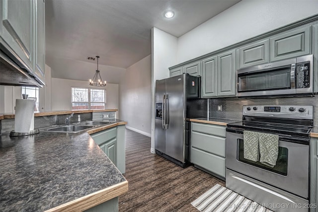 kitchen featuring appliances with stainless steel finishes, a chandelier, sink, dark wood-type flooring, and lofted ceiling