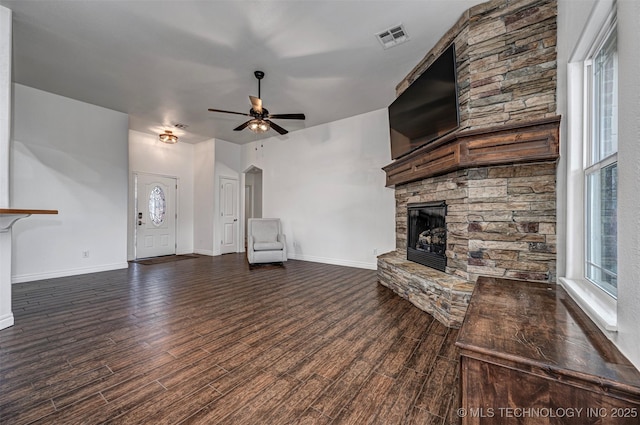 unfurnished living room with ceiling fan and a stone fireplace