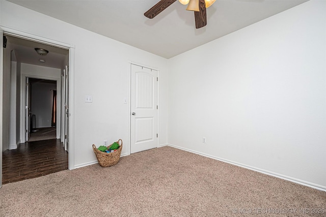 unfurnished bedroom featuring dark colored carpet, a closet, and ceiling fan