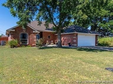 ranch-style house featuring cooling unit, a front yard, and a garage