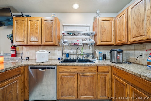 kitchen with brown cabinetry, a sink, and stainless steel dishwasher