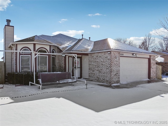 single story home featuring brick siding, a chimney, and an attached garage