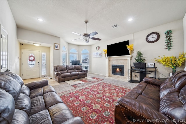 living area featuring a textured ceiling, a tile fireplace, recessed lighting, light colored carpet, and visible vents