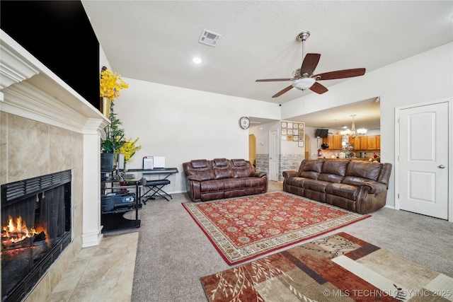 living room with light carpet, ceiling fan with notable chandelier, visible vents, and a tile fireplace