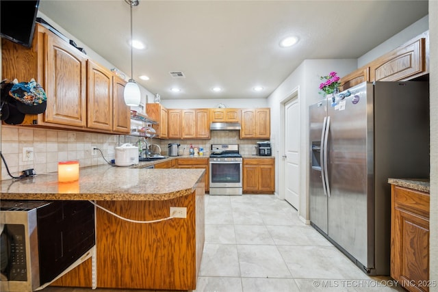 kitchen with pendant lighting, light countertops, appliances with stainless steel finishes, a peninsula, and under cabinet range hood