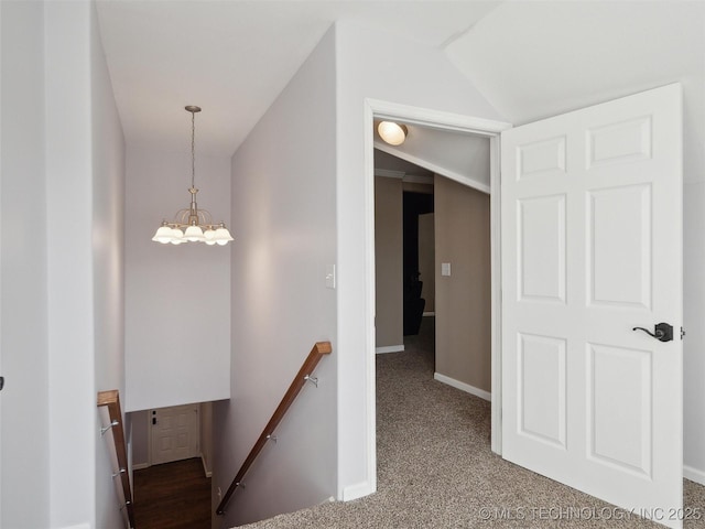 corridor with vaulted ceiling, carpet flooring, and a chandelier