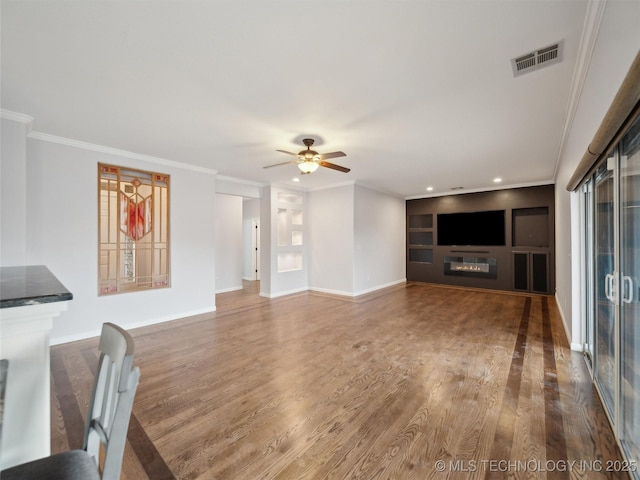 unfurnished living room featuring ceiling fan, hardwood / wood-style floors, built in features, and crown molding