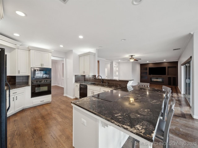 kitchen with white cabinetry, kitchen peninsula, tasteful backsplash, dark hardwood / wood-style flooring, and black appliances