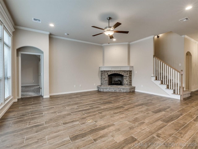 unfurnished living room with crown molding, a stone fireplace, and a healthy amount of sunlight