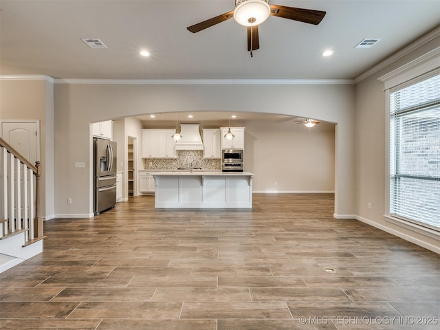 kitchen with premium range hood, ceiling fan, stainless steel appliances, backsplash, and ornamental molding