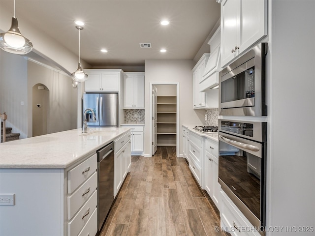 kitchen featuring white cabinets, backsplash, appliances with stainless steel finishes, and pendant lighting