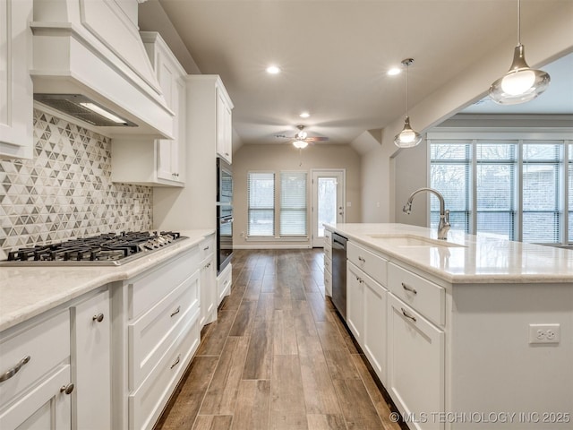 kitchen featuring decorative light fixtures, sink, white cabinetry, appliances with stainless steel finishes, and custom range hood