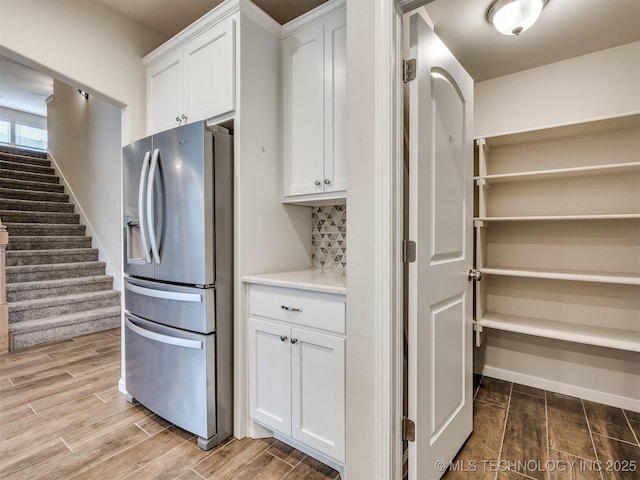 kitchen with backsplash, white cabinets, and stainless steel fridge with ice dispenser