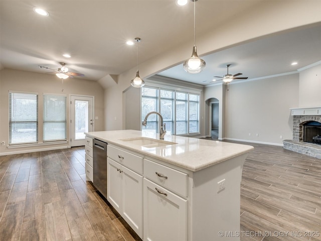 kitchen with decorative light fixtures, a kitchen island with sink, dishwasher, white cabinets, and sink