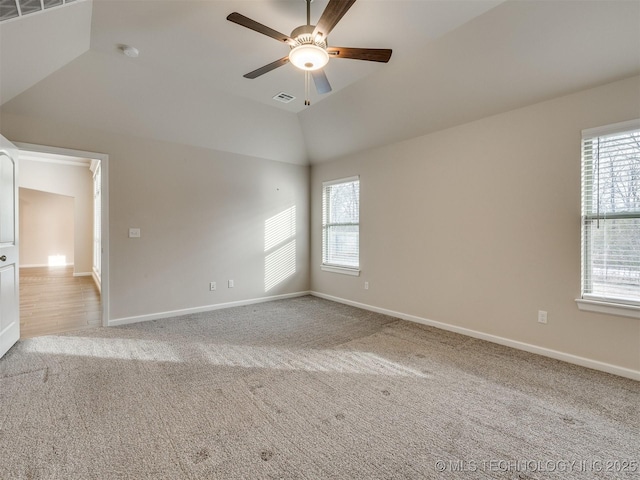 spare room with light carpet, a healthy amount of sunlight, vaulted ceiling, and ceiling fan