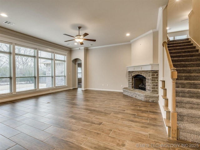 unfurnished living room featuring ceiling fan, a fireplace, and ornamental molding