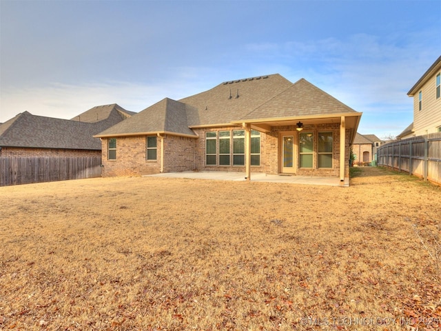 rear view of house with ceiling fan, a yard, and a patio