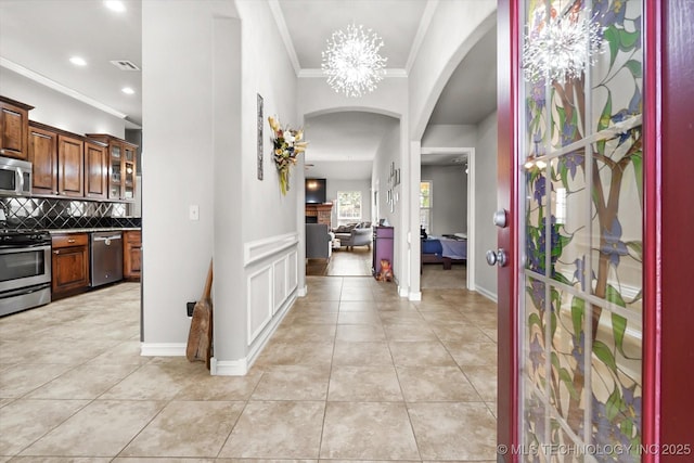 tiled foyer with crown molding and a chandelier