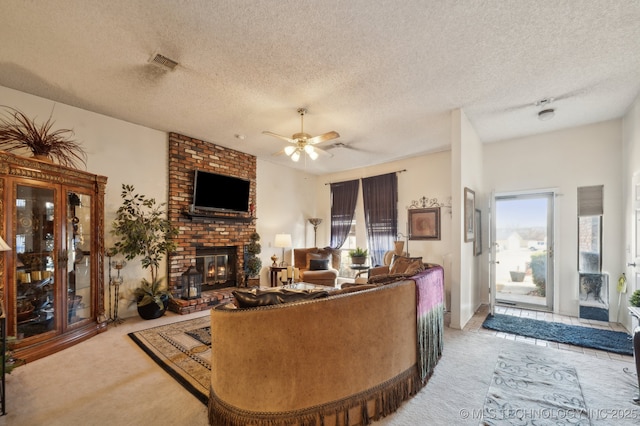 carpeted living room featuring ceiling fan, plenty of natural light, a fireplace, and a textured ceiling