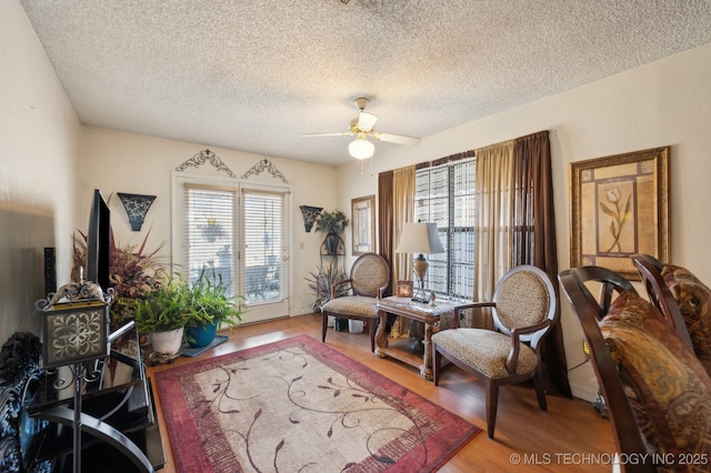 sitting room featuring wood-type flooring, a healthy amount of sunlight, ceiling fan, and a textured ceiling