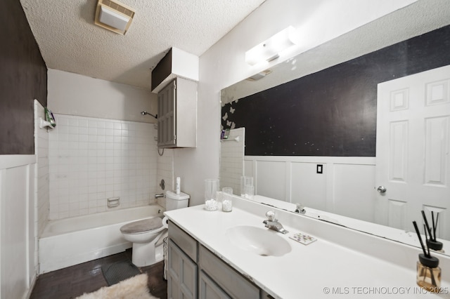 full bathroom featuring tiled shower / bath, vanity, toilet, and a textured ceiling