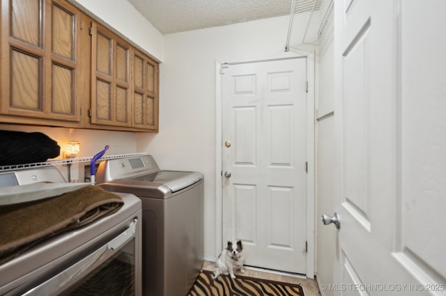 clothes washing area featuring cabinets, washer and dryer, and a textured ceiling