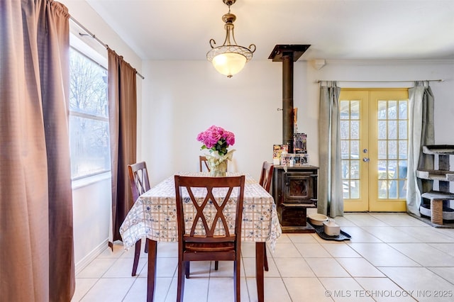 dining room with light tile patterned floors, french doors, and a wood stove