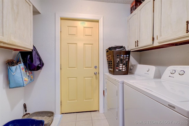 clothes washing area with washing machine and dryer, cabinets, and light tile patterned flooring