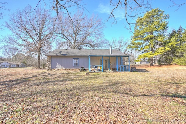 rear view of house featuring covered porch and a yard