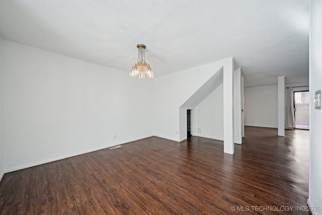 unfurnished living room with a textured ceiling, dark hardwood / wood-style floors, and a chandelier