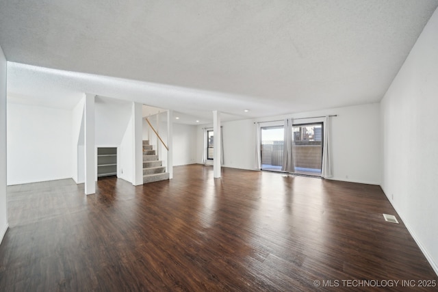 unfurnished living room with a textured ceiling and dark hardwood / wood-style flooring