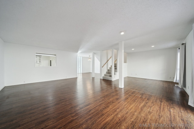 unfurnished living room with a textured ceiling and dark hardwood / wood-style floors