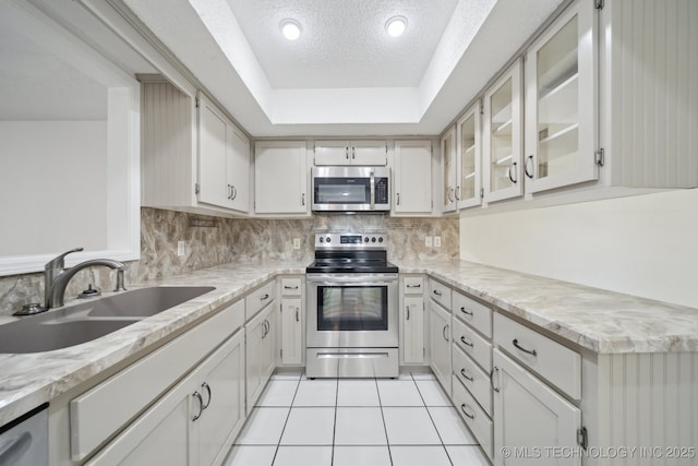 kitchen featuring a raised ceiling, sink, appliances with stainless steel finishes, backsplash, and light tile patterned flooring