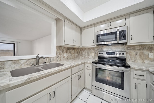 kitchen with sink, white cabinetry, stainless steel appliances, and tasteful backsplash