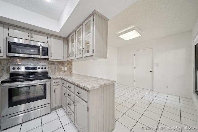 kitchen featuring decorative backsplash, a textured ceiling, light tile patterned floors, and stainless steel appliances