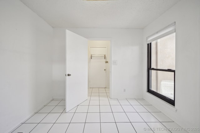 spare room with a textured ceiling and light tile patterned floors