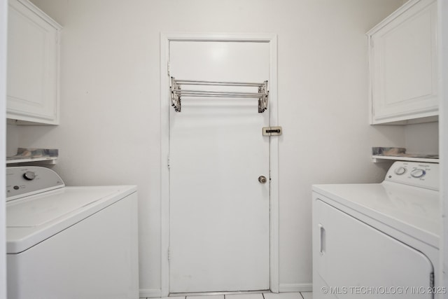 clothes washing area featuring light tile patterned floors, cabinets, and washer and dryer